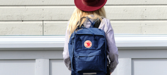 Szőke nő kalapban, kék Fjällräven hátizsákkal