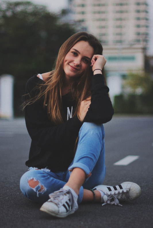 Lány ül az út közepén egy Adidas Superstar cipőben