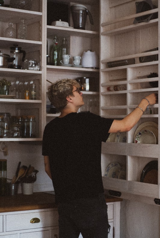 Egy férfi fekete pólóban pakol a konyhaszekrényben