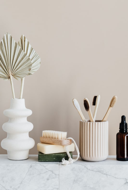 Fenntartható szappanok, kefe, bambusz fogkefe, fehér váza bézs háttér előtt