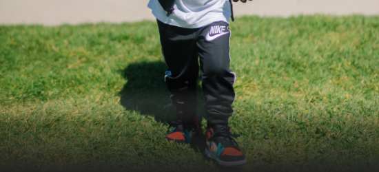 Fiú Nike melegítőben és színes tornacipőben a fűben